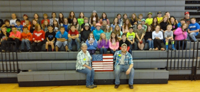 5th grade students with Kitty Davis and Teddy Hill holding an American Flag made out of scrap tin